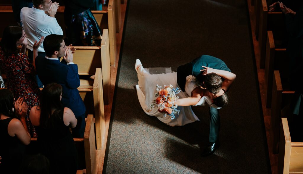 Groom dip's the bride as they walk back down the aisle 