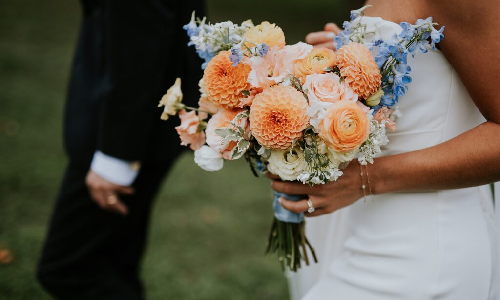 a close up of the bride's gorgeous colorful bouquet, lots of orange with pops of pink and blue.