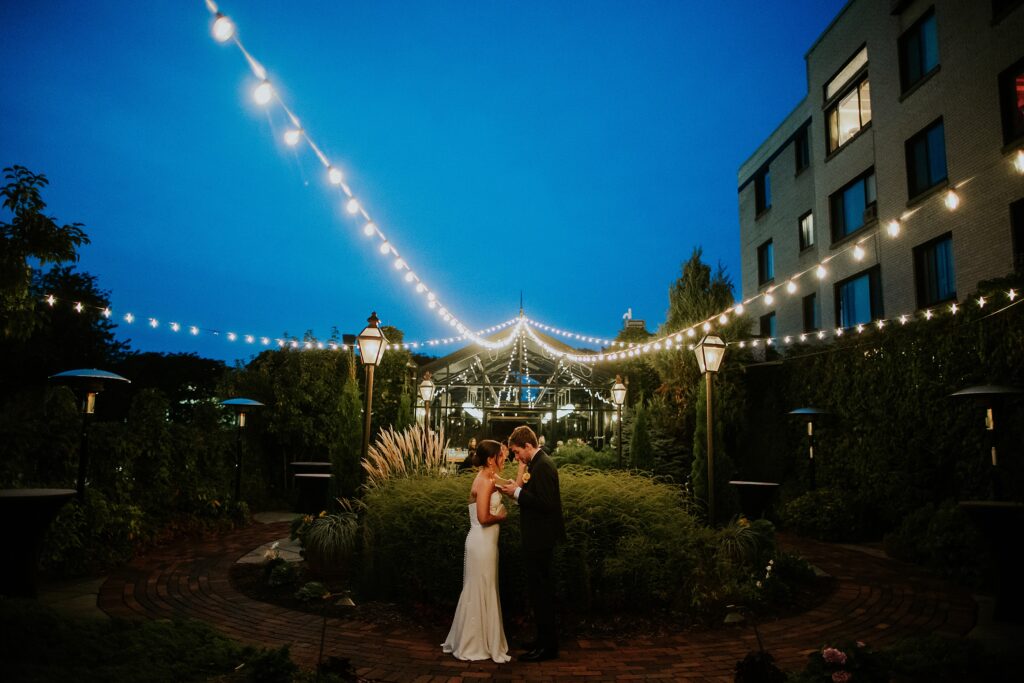 Private vows being read by the bride and groom under the string lights on the rooftop garden at the Atrium